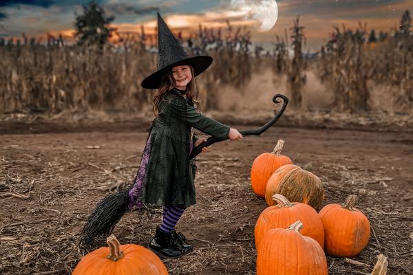 girl witch on broom in a pumpkin patch